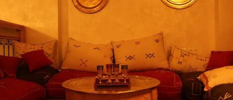 A cozy room with a sofa set, a small round table with glasses, and decorative pillows.