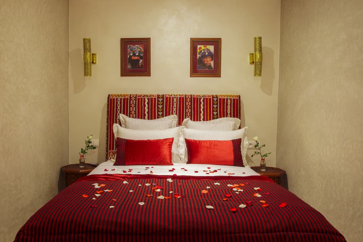 A neatly made bed with red and black striped bedding, two pillows, and a decorative headboard.