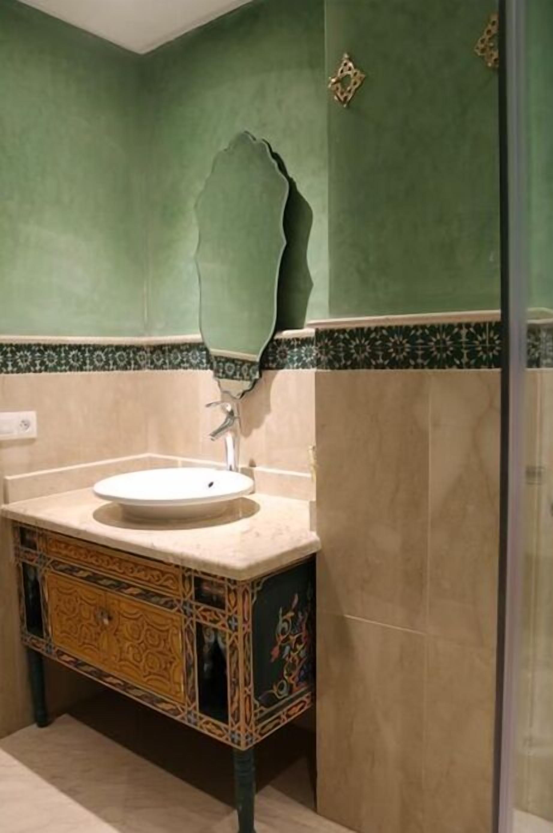Un baño con un lavabo, un mueble decorativo y una pared verde.