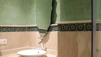 Un baño con un lavabo, un mueble decorativo y una pared verde.