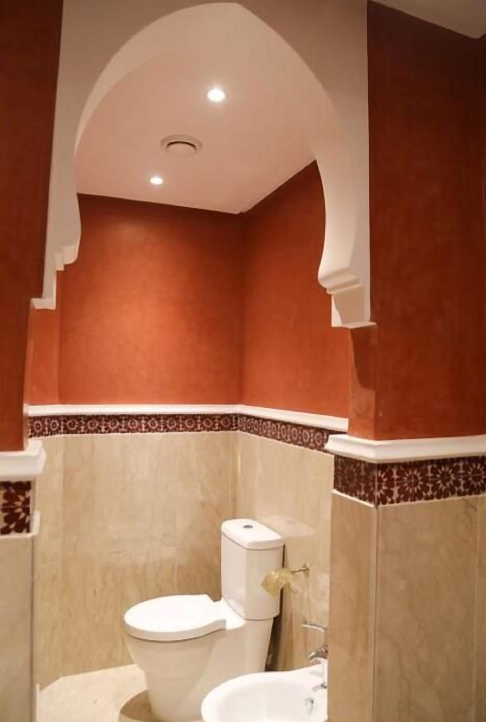 A bathroom with a toilet, sink, and a decorative archway.
