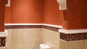 Un baño con inodoro, lavamanos y un arco decorativo.