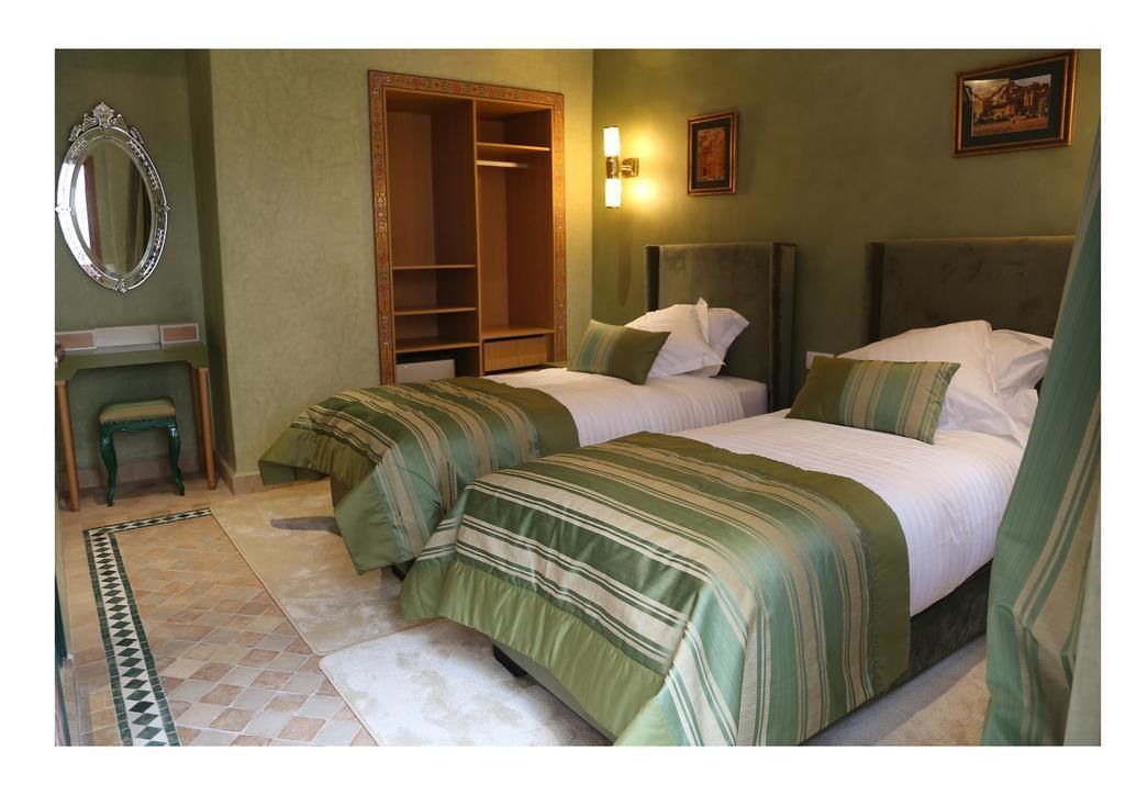 Habitación de hotel con dos camas, un armario, un espejo y una mesita.