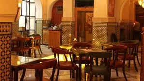 An interior with a high ceiling, ornate chandeliers, and a central staircase. Tables and chairs are arranged for dining. - Palais Zahia (Tangier)