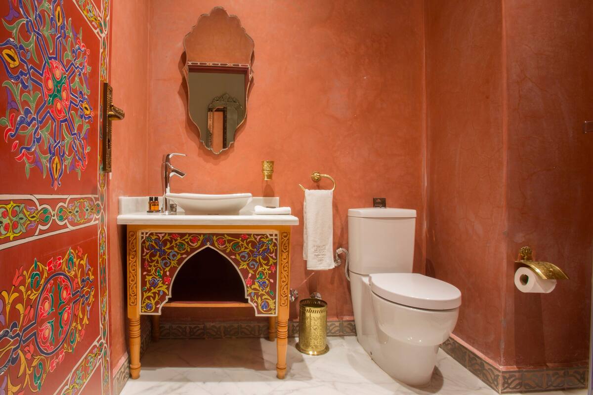 A bathroom with a sink, toilet, and decorative wall.