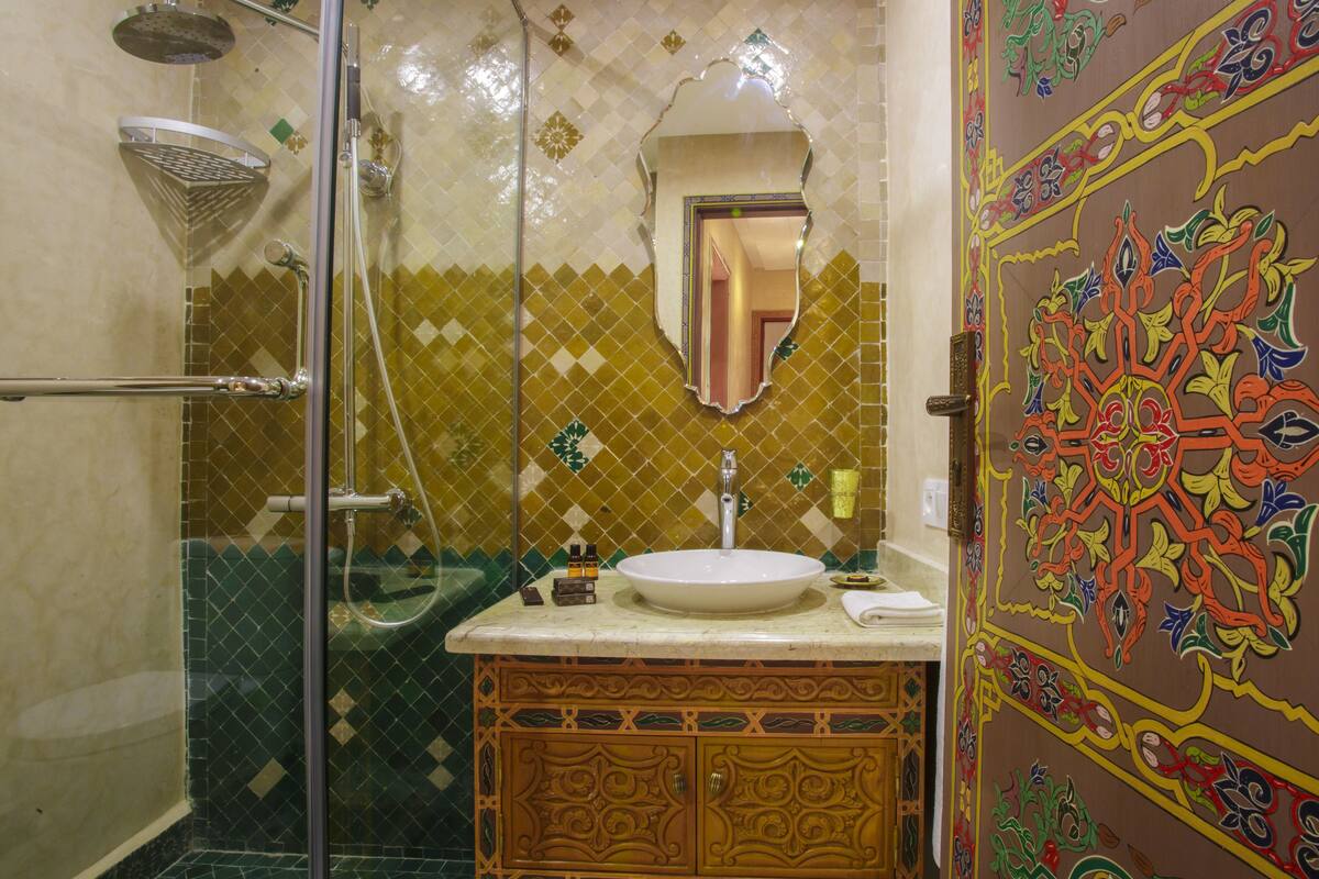 A bathroom with a glass shower enclosure, a sink with a mirror, and a decorative door.