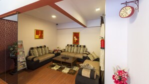 A modern living room with a sofa set, a coffee table, and a wall-mounted clock. - Hotel Raj Comforts - Golf View (Bengaluru)
