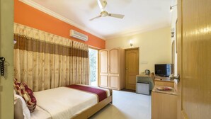 A hotel room with a bed, a desk with a telephone, a television, and a kitchenette. - Hotel Raj Comforts - Golf View (Bengaluru)