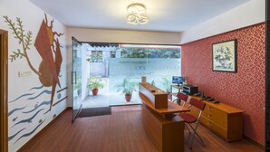 A reception area with a wooden desk, chairs, a computer, and a potted plant. - Hotel Raj Comforts - Golf View (Bengaluru)