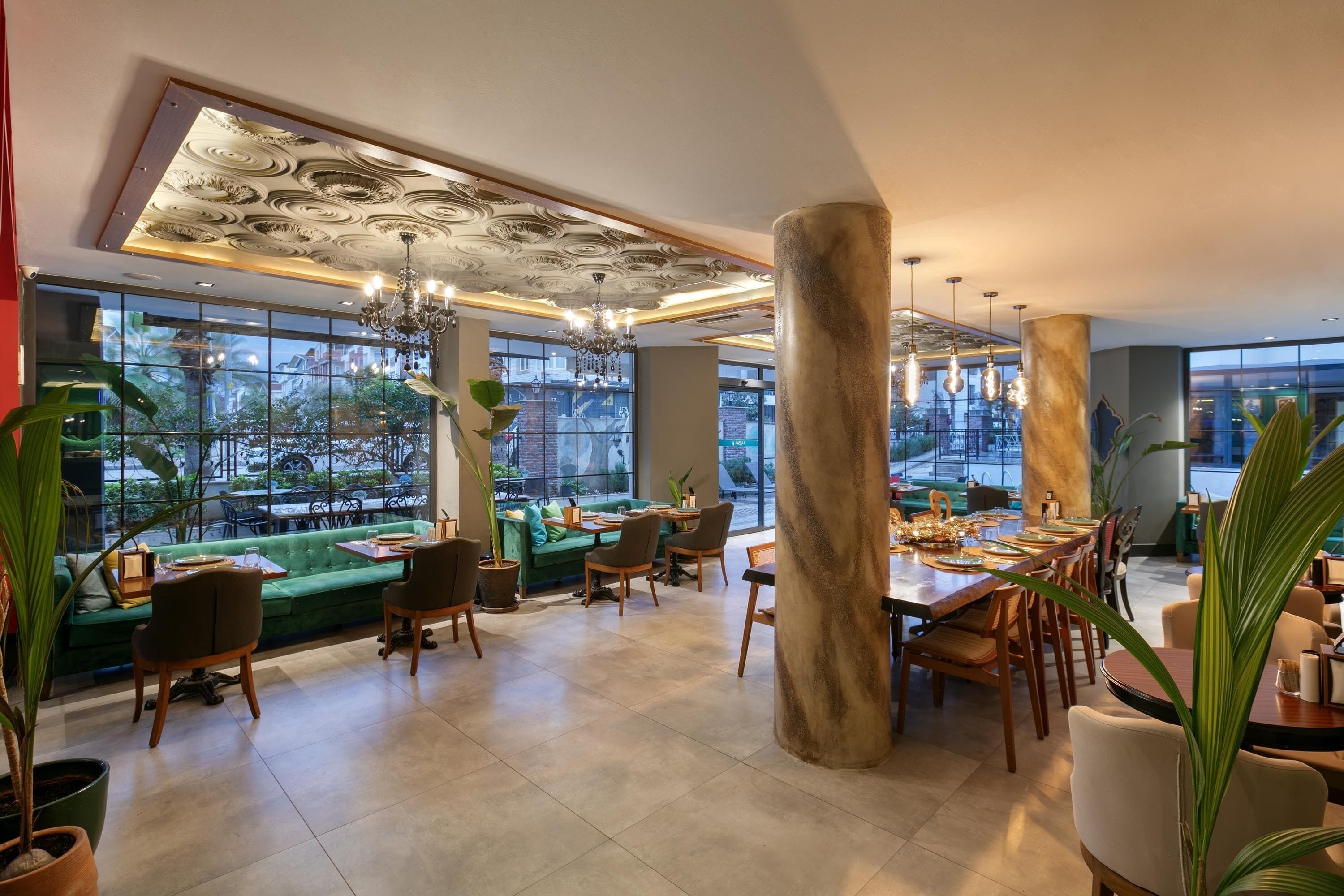 A modern restaurant with a green sofa, wooden chairs, and a large dining table.