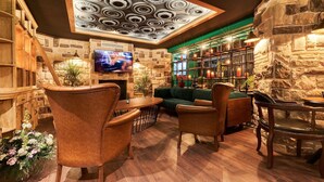 Un salon confortable avec un mur en pierre, une cheminée et un téléviseur.