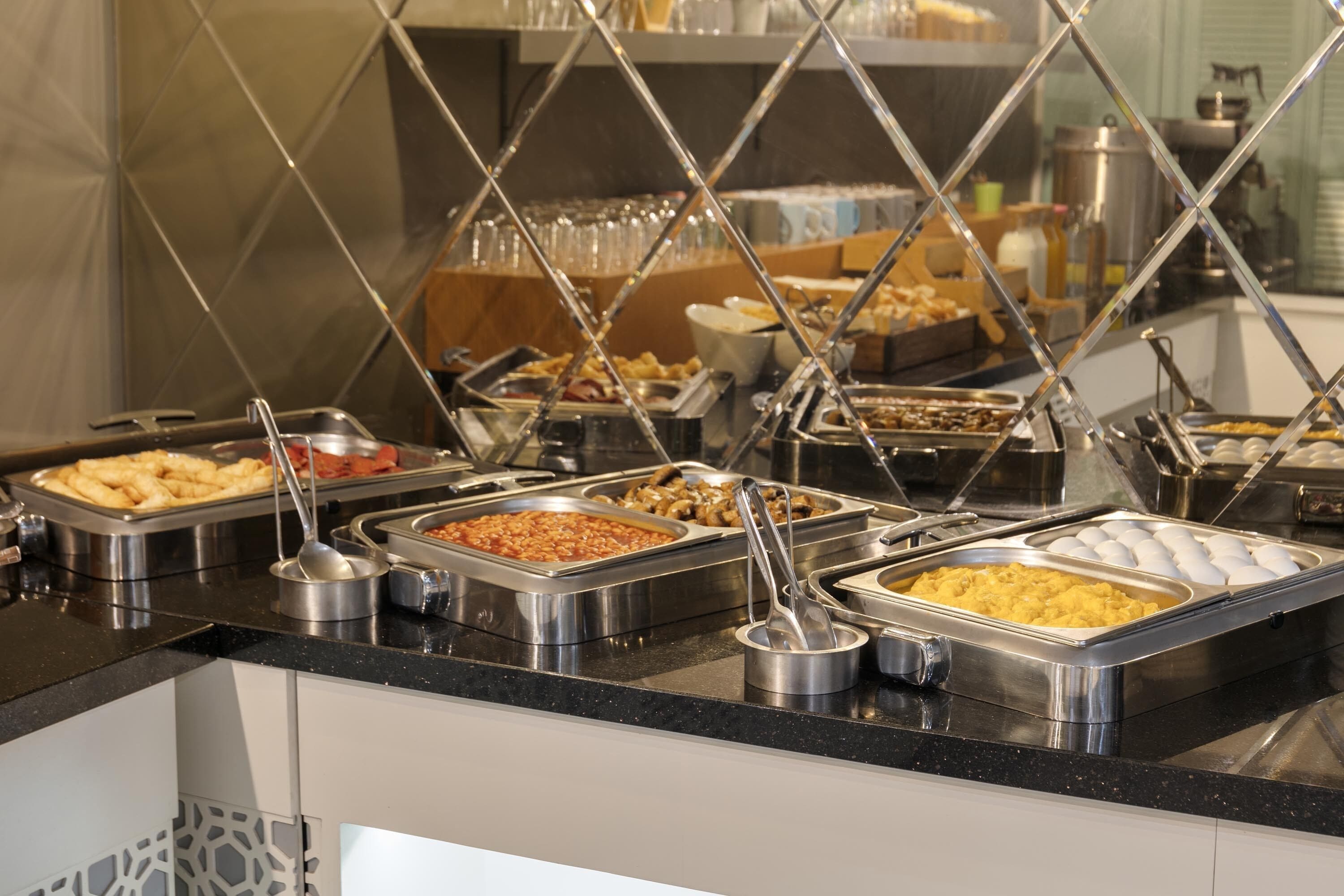 Um buffet com diversas opções de comida, incluindo massa, ovos e outros pratos.