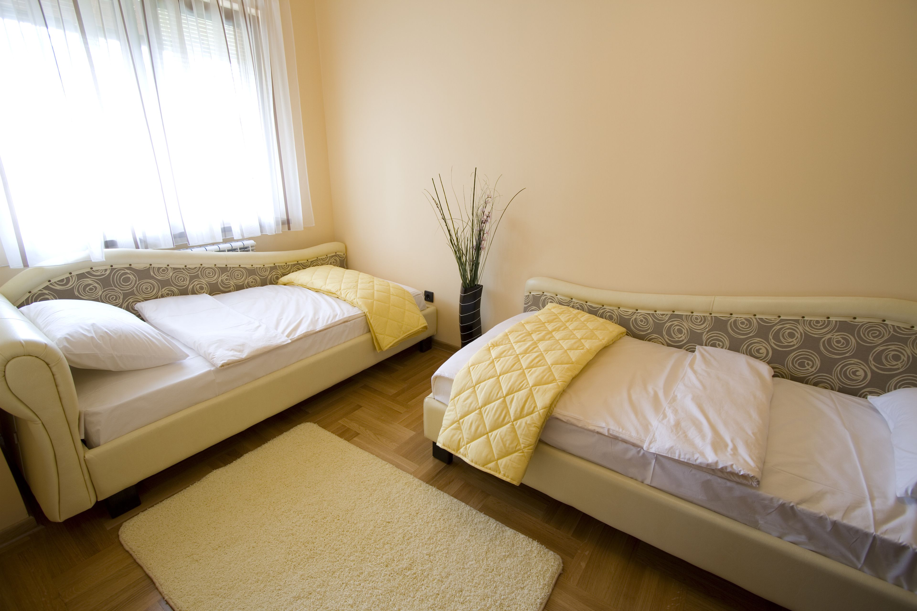 Una habitación con dos camas, una mesita y una ventana con cortinas.