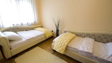 Una habitación con dos camas, una mesita y una ventana con cortinas.