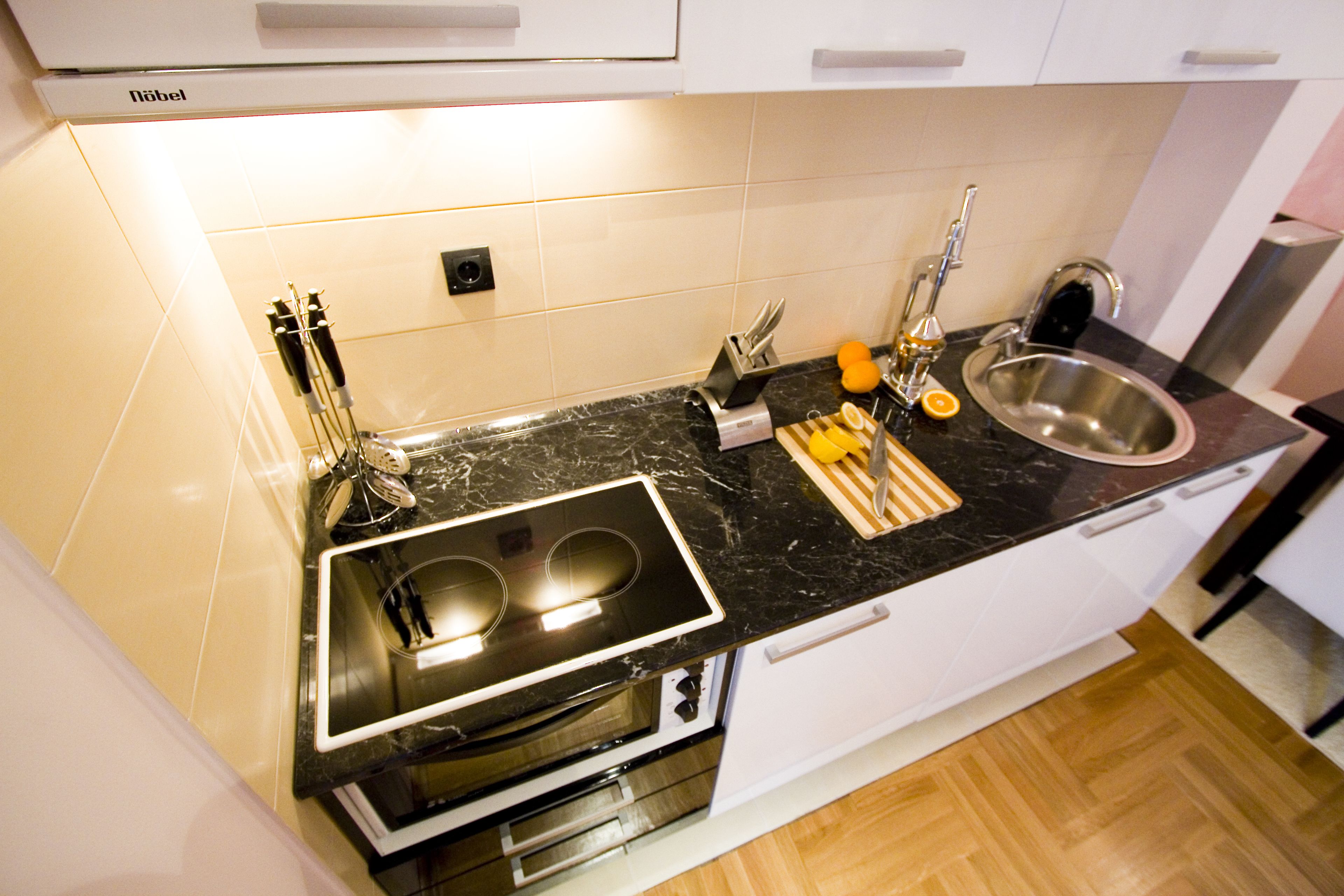 A modern kitchen with a black countertop, stainless steel sink, and built-in oven.