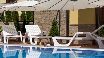A pool area with lounge chairs and umbrellas.