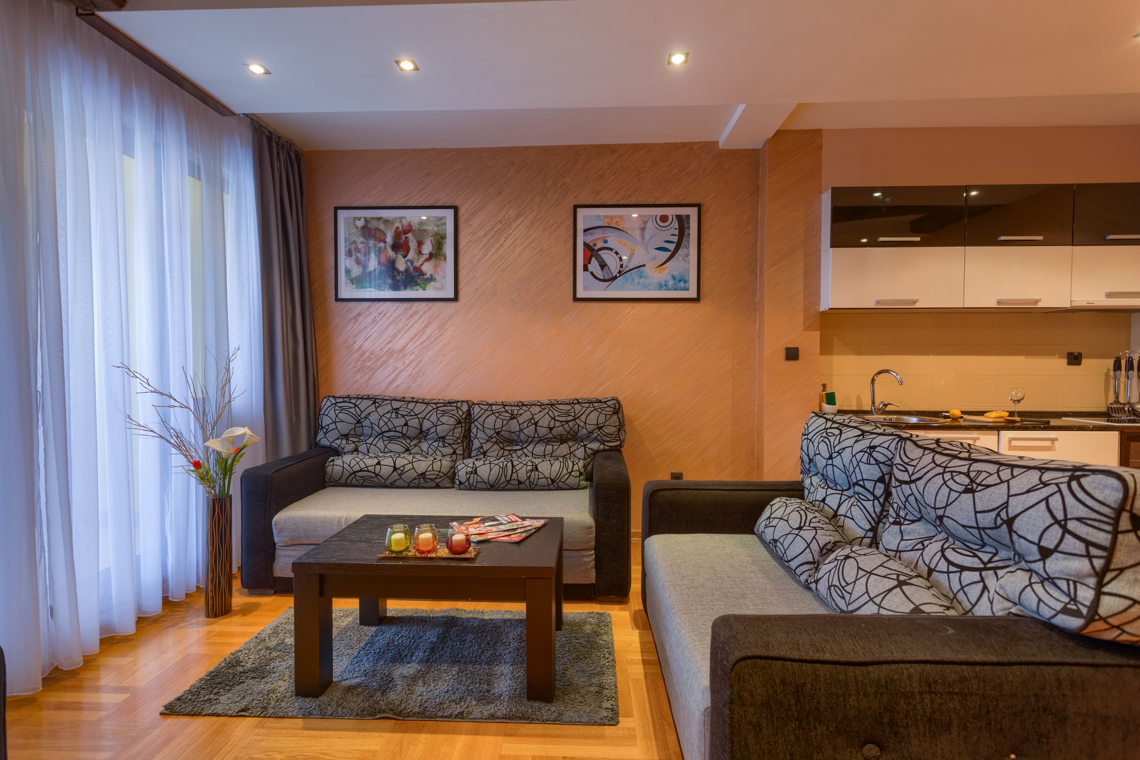 A modern living room with a sofa, a coffee table, and a dining area with a kitchen in the background.