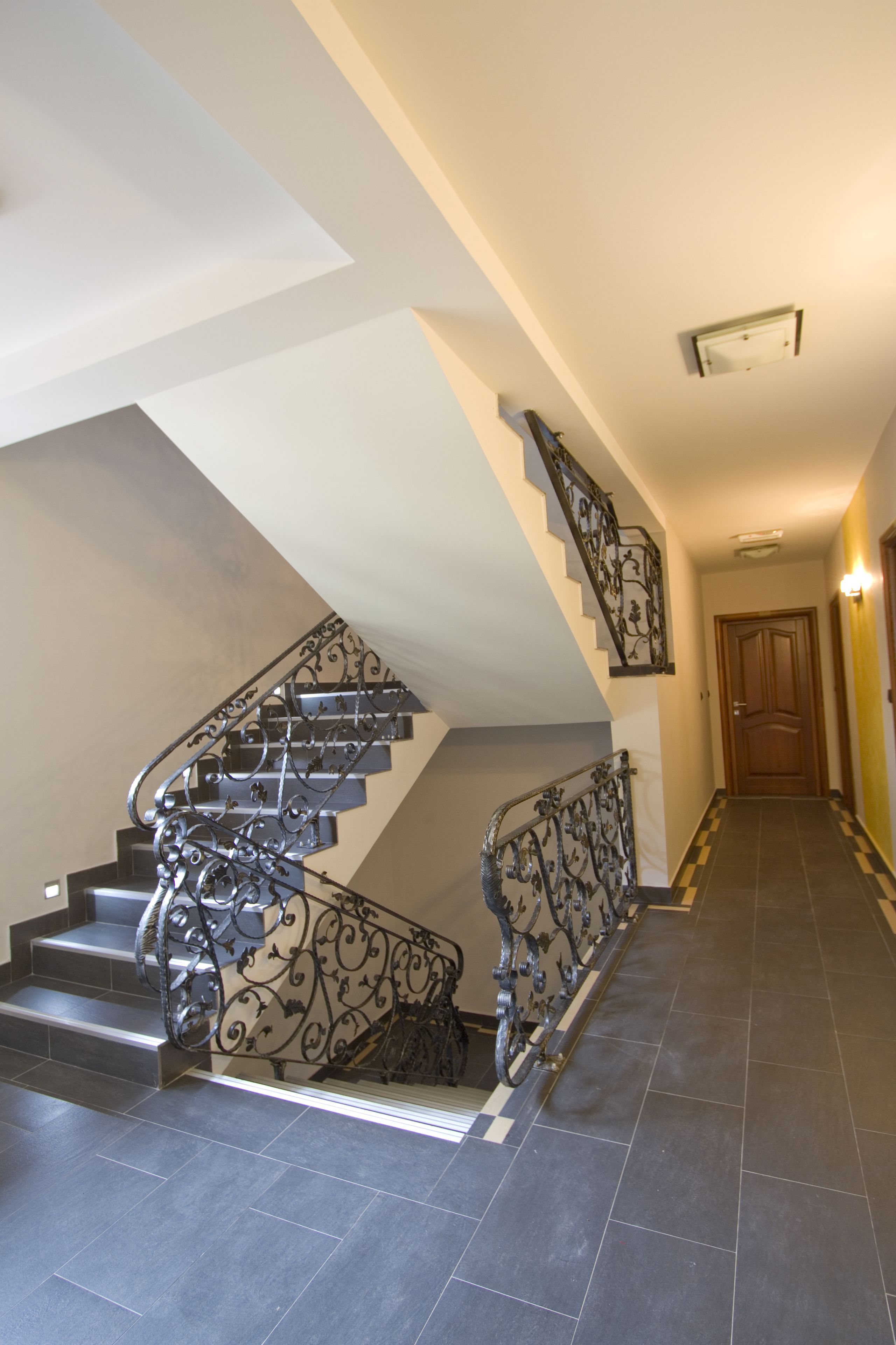A staircase with ornate metal railings and a checkered floor pattern.
