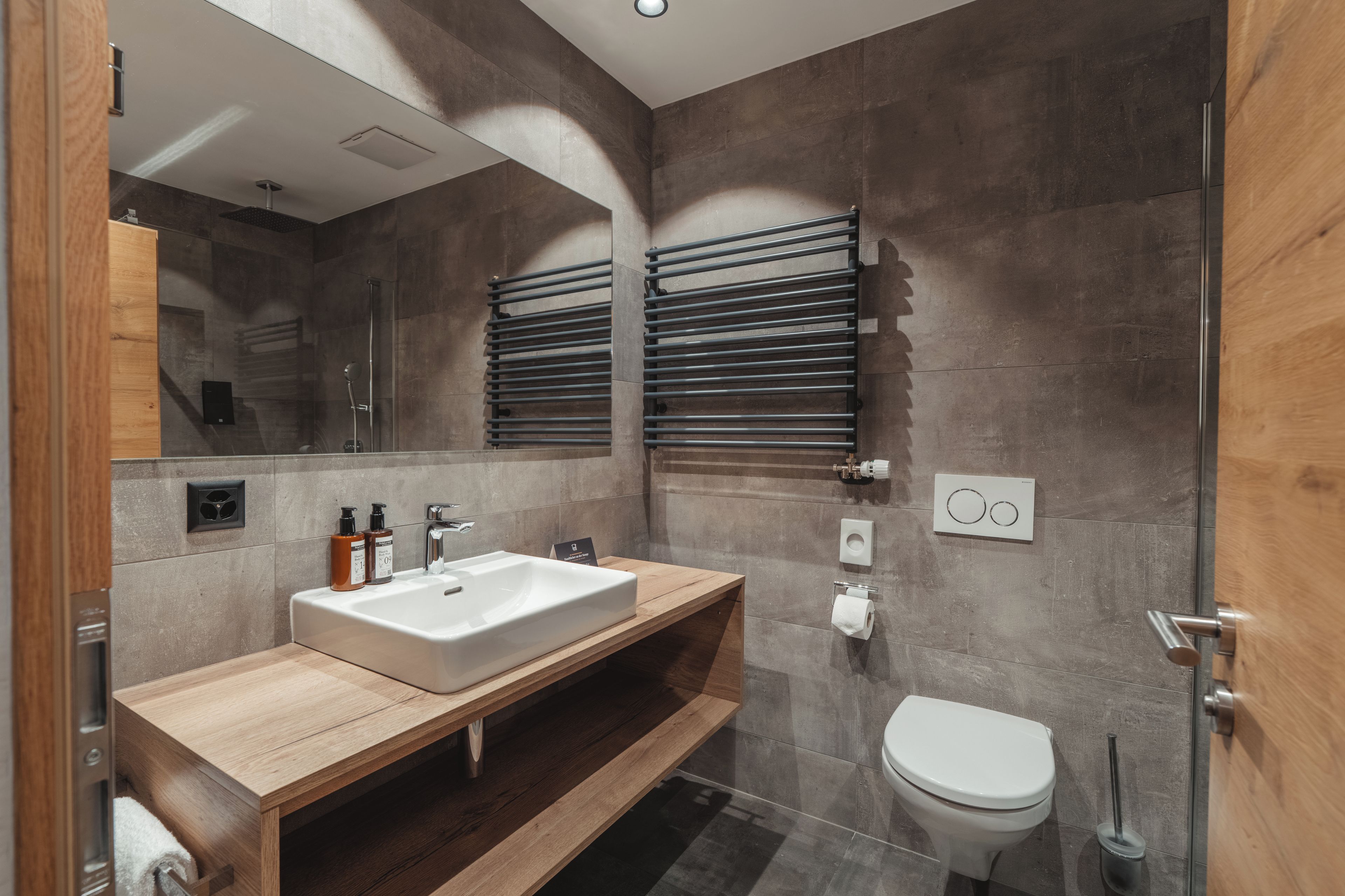 A modern bathroom with a large mirror, a sink, and a toilet.