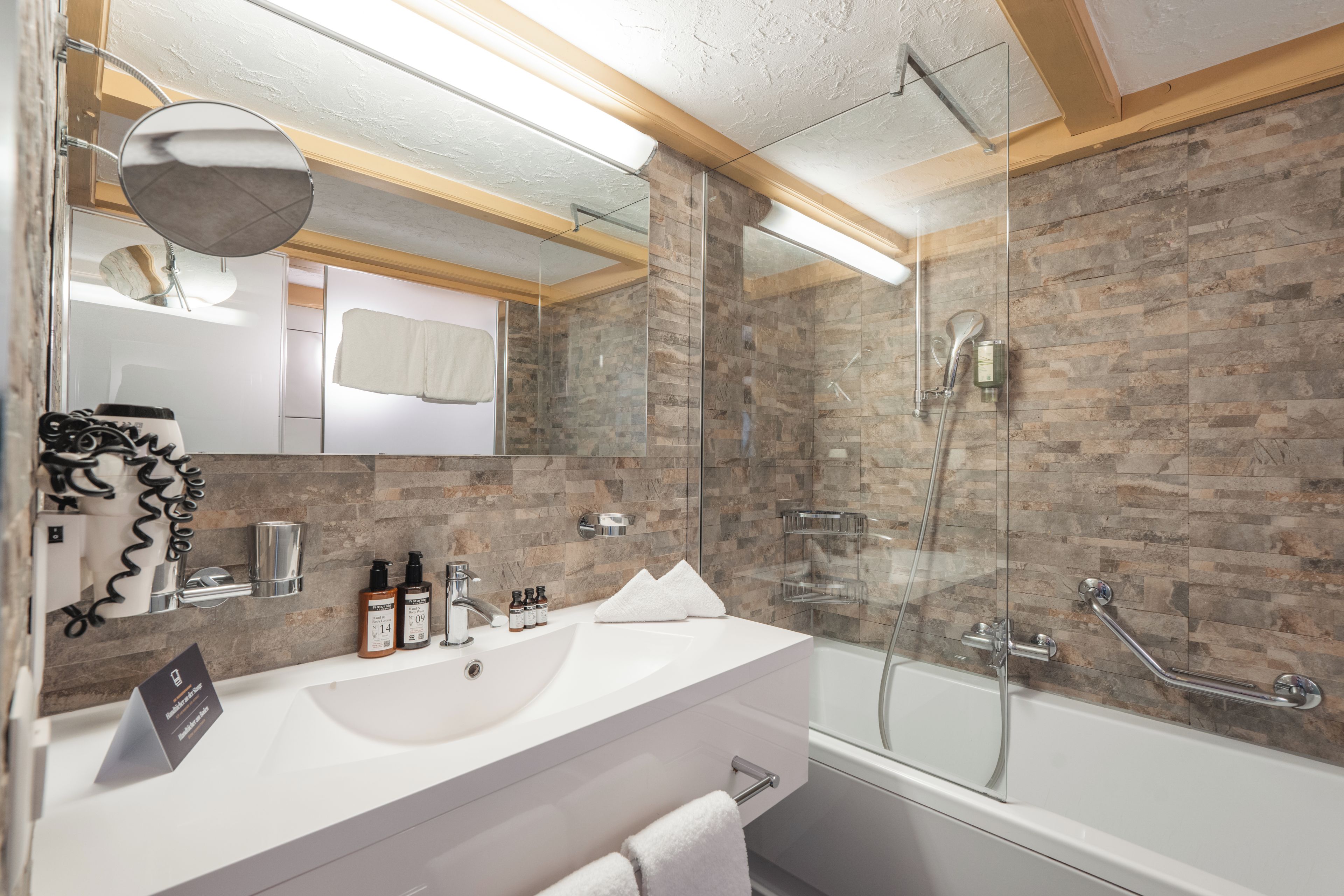 A modern bathroom with a white sink, a glass shower enclosure, and a mirror above the sink.
