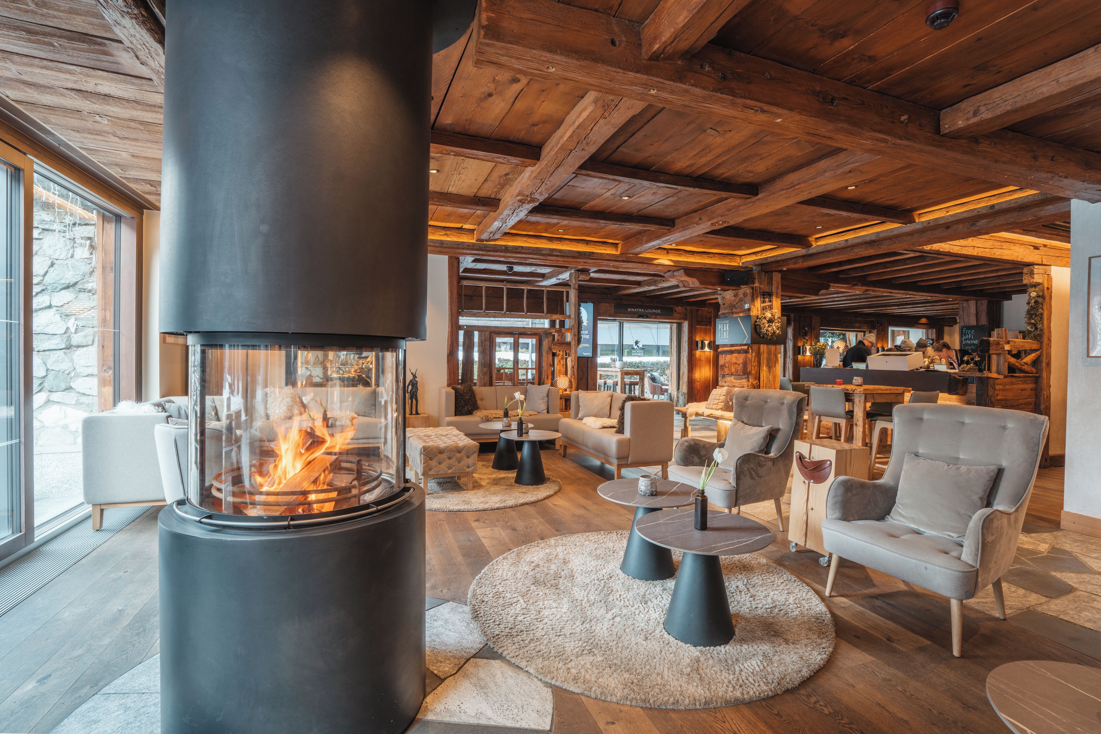 A cozy lounge area with a wood-burning stove, comfortable seating, and a stone wall.