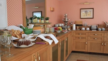 A kitchen with wooden cabinets, a countertop with various food items, a sink, and a mirror.