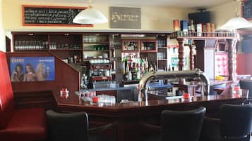 Un área de bar con mobiliario de madera, estantes con botellas y un menú en una pizarra.
