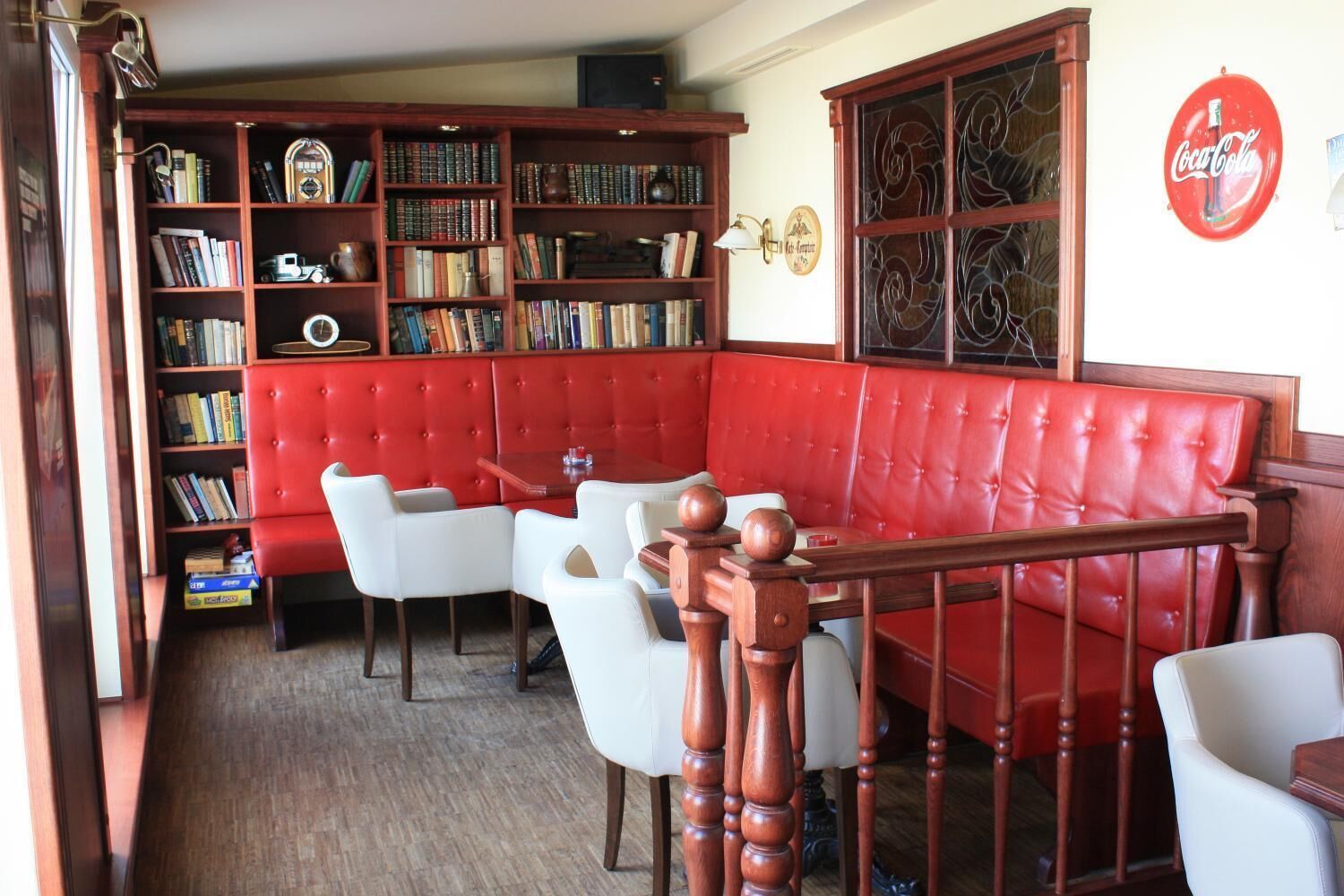 Une bibliothèque avec des sièges en cuir rouge, des chaises blanches et un escalier en bois.