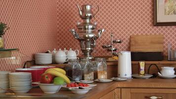 Una encimera de cocina con un juego de té, fruta y diversos utensilios.