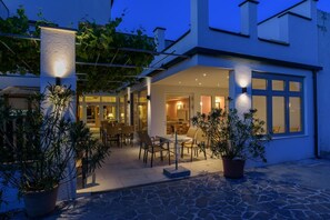 Una casa moderna con un porche cubierto, suelo de piedra y plantas en macetas.