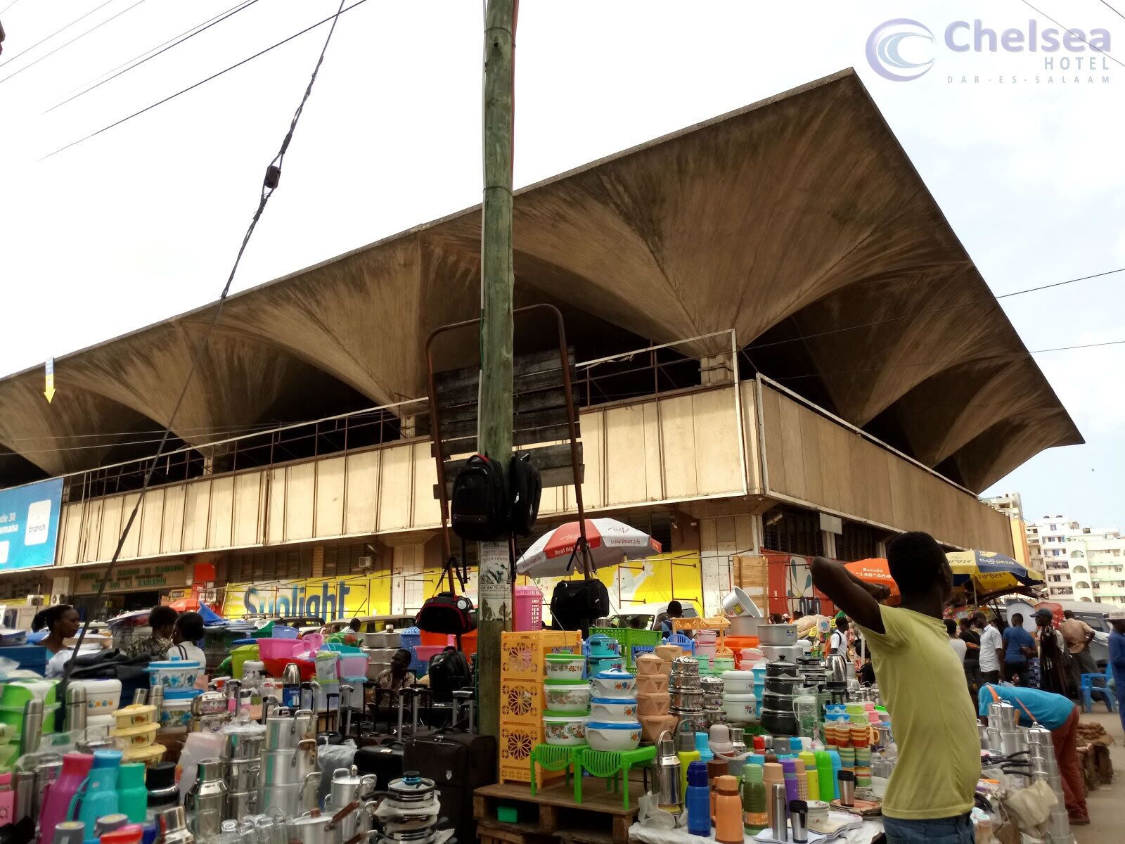 A market area with various stalls selling household items.