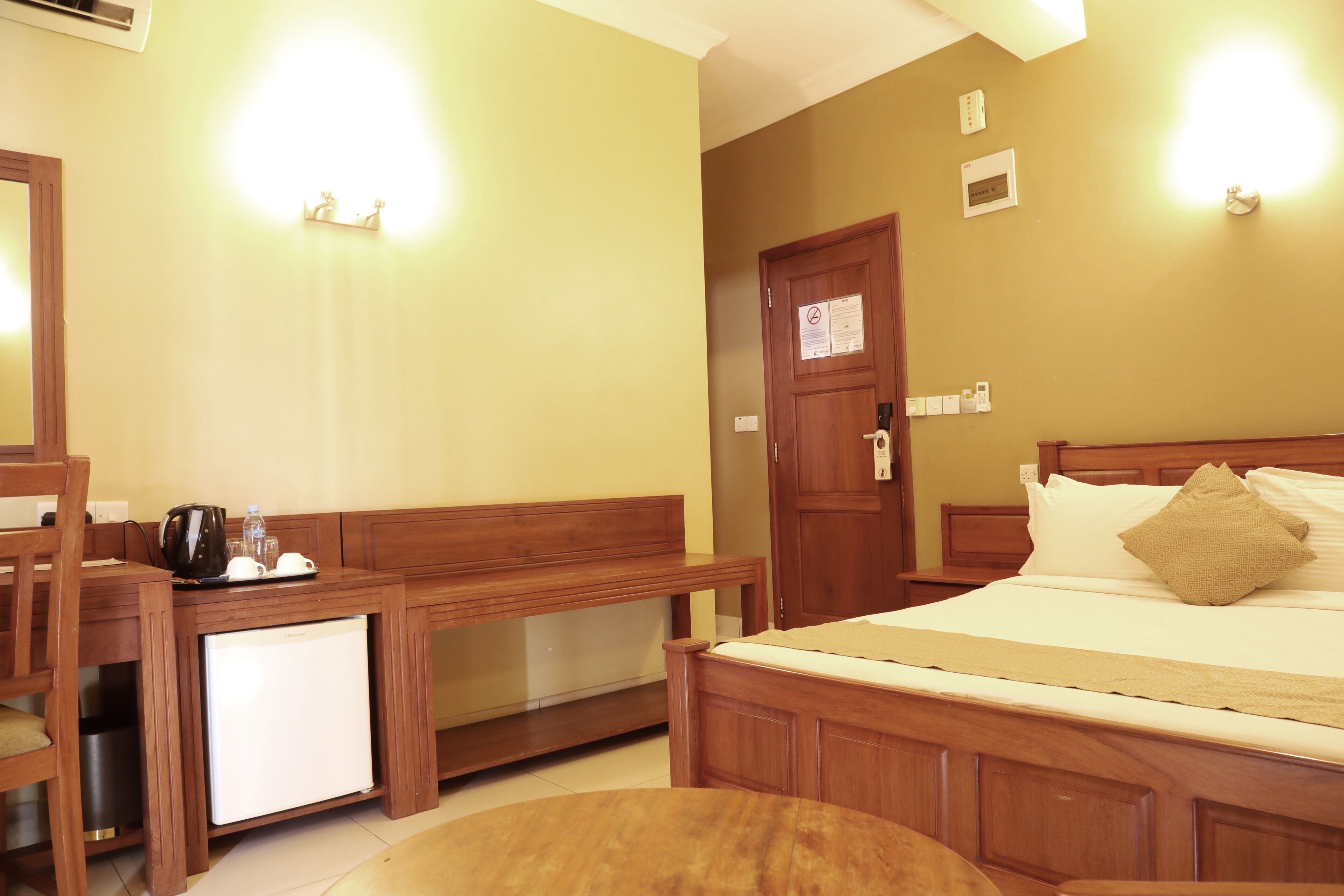 Een hotelkamer met een houten bed, een klein bureau met een koelkast en een bank.