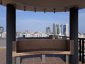 A rooftop terrace with a view of a city skyline, featuring modern buildings and a clear sky. - Chelsea Hotel (Dar es Salaam)