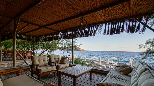 Un espace extérieur aménagé avec du mobilier en bois et offrant une vue sur l’océan.