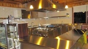 Une cuisine moderne dotée d’appareils électroménagers en acier inoxydable, d’un grand îlot central et de luminaires suspendus.