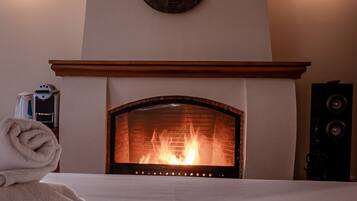 Habitación de hotel con chimenea, una cama con una toalla enrollada e iluminación empotrada.