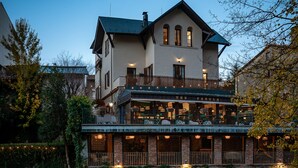 Un bâtiment à deux étages doté d’un balcon, d  ’un mur en pierre et d’une rivière en premier plan.