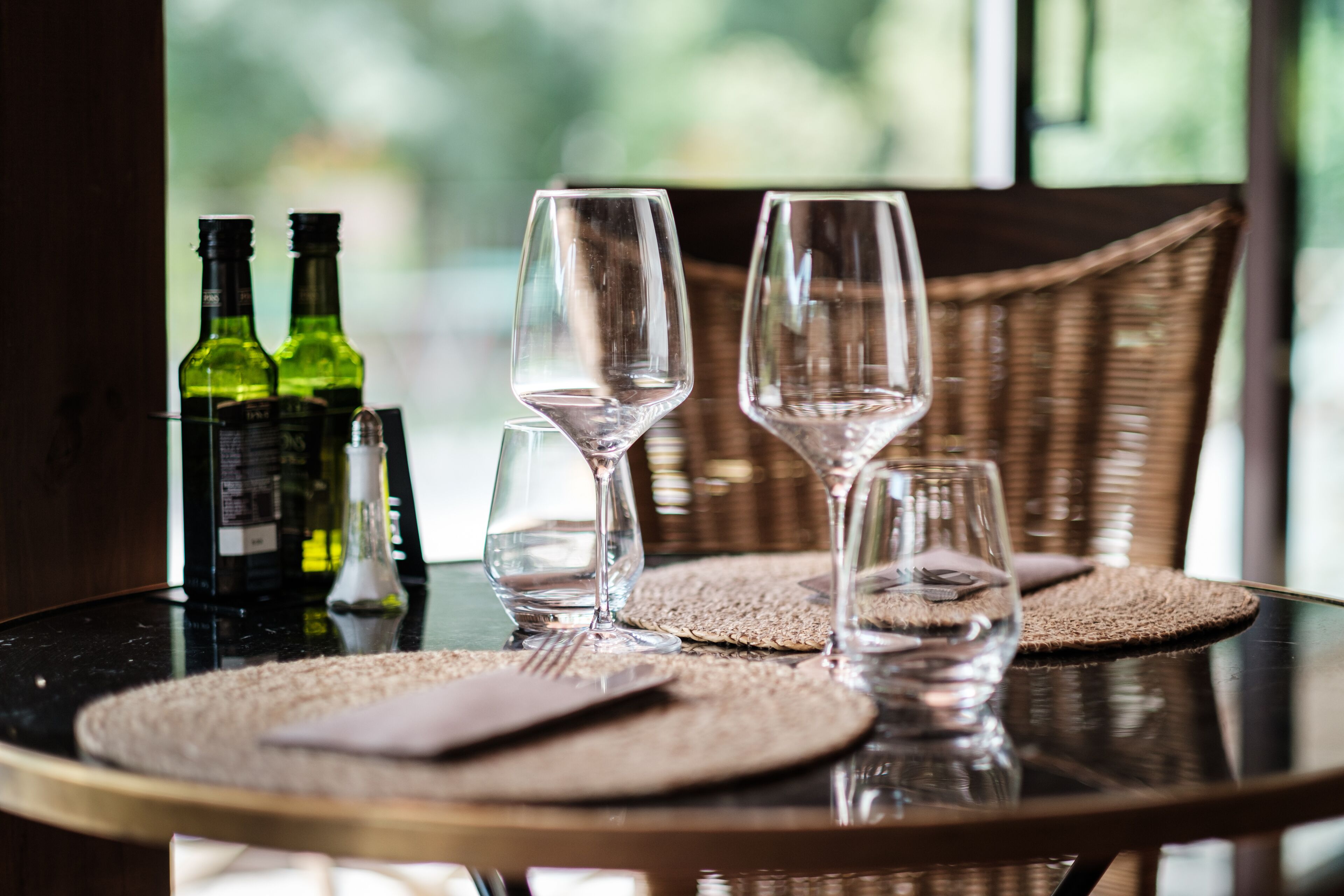 A dining table with two wine glasses, a bottle of wine, and a bottle of olive oil.