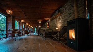 Un intérieur rustique avec un mur en pierre, un plafond en bois et un poêle à bois.