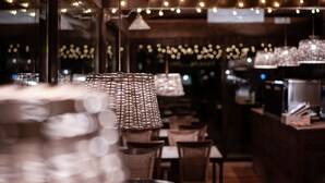 L’intérieur d’un restaurant, avec des guirlandes lumineuses suspendues, des lampes en osier et un coin bar.