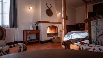 A cozy room with a fireplace, wooden furniture, and a bed with a floral bedspread.