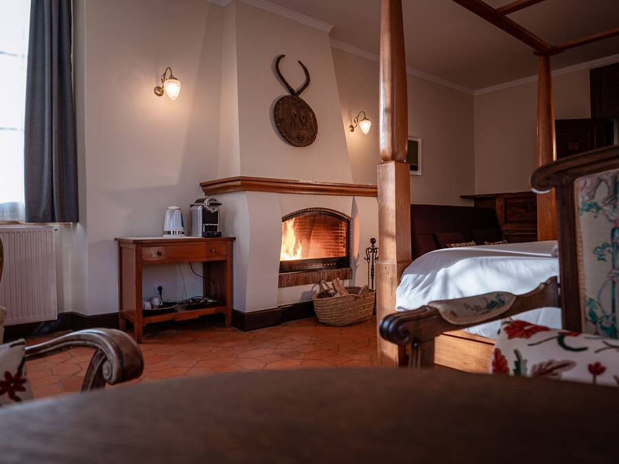 A cozy room with a fireplace, wooden furniture, and a bed with a floral bedspread.