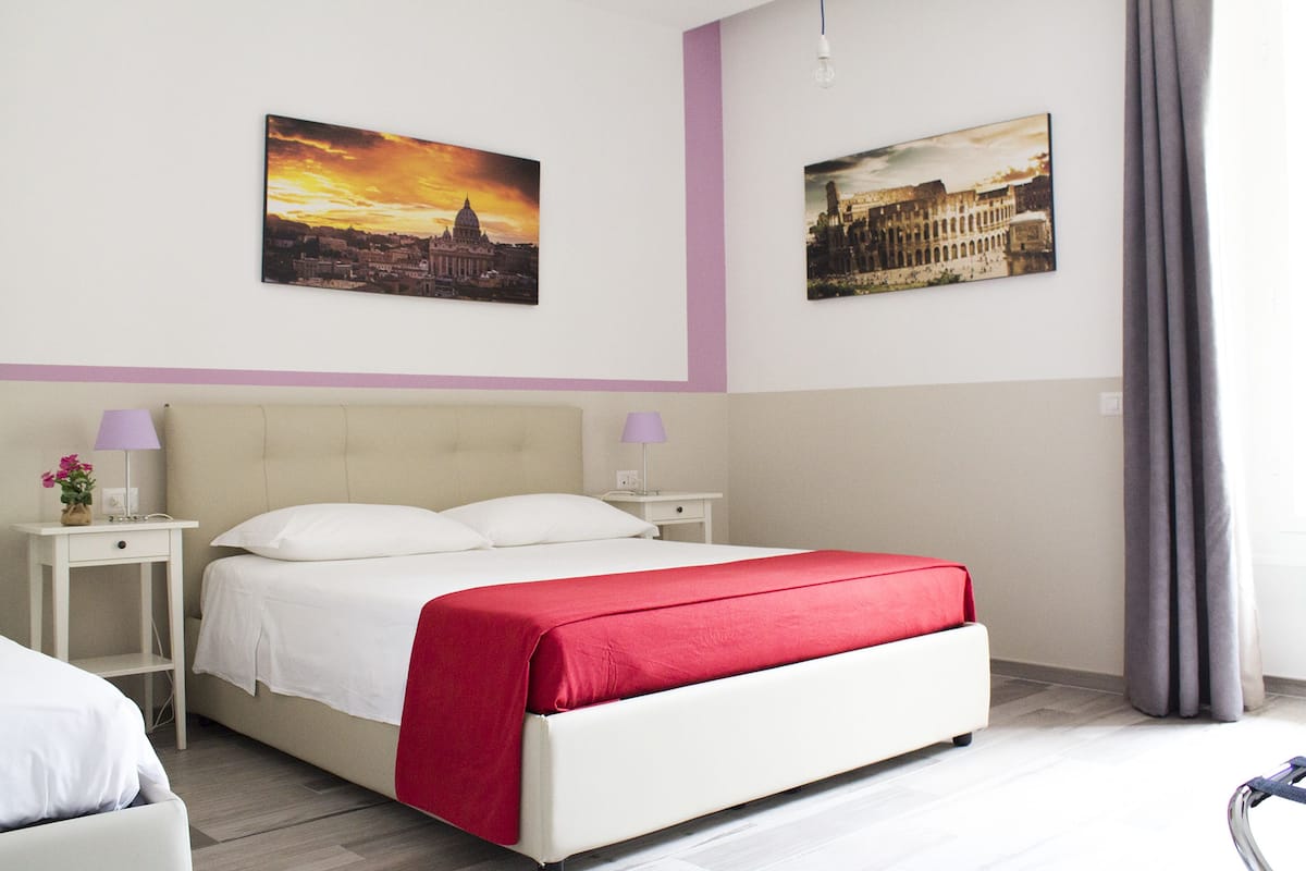A hotel room with a bed, two nightstands, a lamp, and two paintings on the wall.