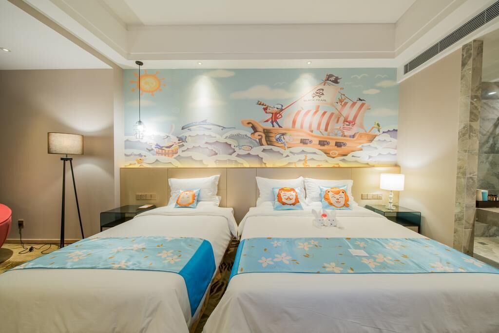 A hotel room with two beds, a mural of a pirate ship, and a red chair.