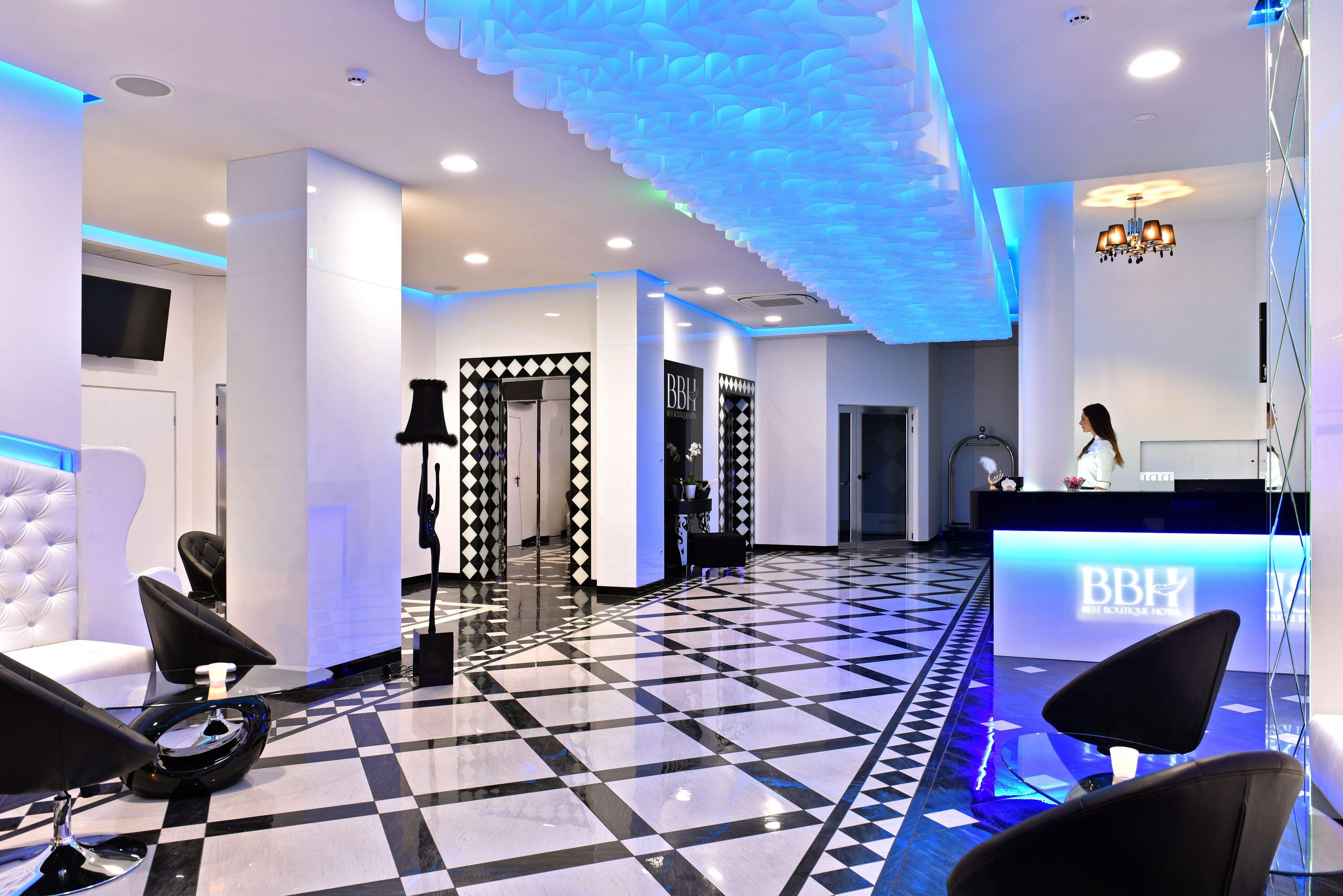 A hotel reception area with a check-in desk, black and white checkered floor, and modern decor.