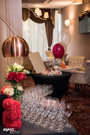 A table set with multiple wine glasses, a menu, and balloons in a room with a chandelier and a tufted armchair. - Best Boutique Hotel (Shanghai)