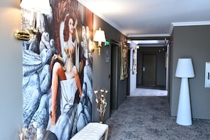 A hallway with a mural, a bench, and a lamp. - Best Boutique Hotel (Shanghai)