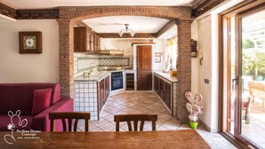 Una cocina con piso de baldosas, armarios de madera y un comedor con mesa y sillas.