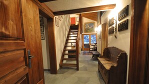 Eine HolztTreppe führt zu einer zweiten Etage, eine hölzerne Bank und eine Tür mit einem Griff.