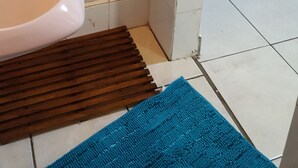 A bathroom with a shower, a sink, and a wooden bench. - Indigo Guesthouse (Pinetown)